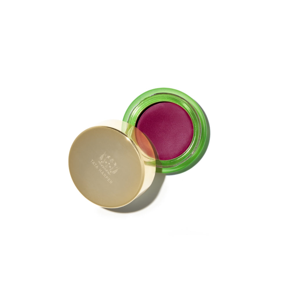 A pot of bright pink lip and cheek tint with a golden lid, shown at an angle on a white background.